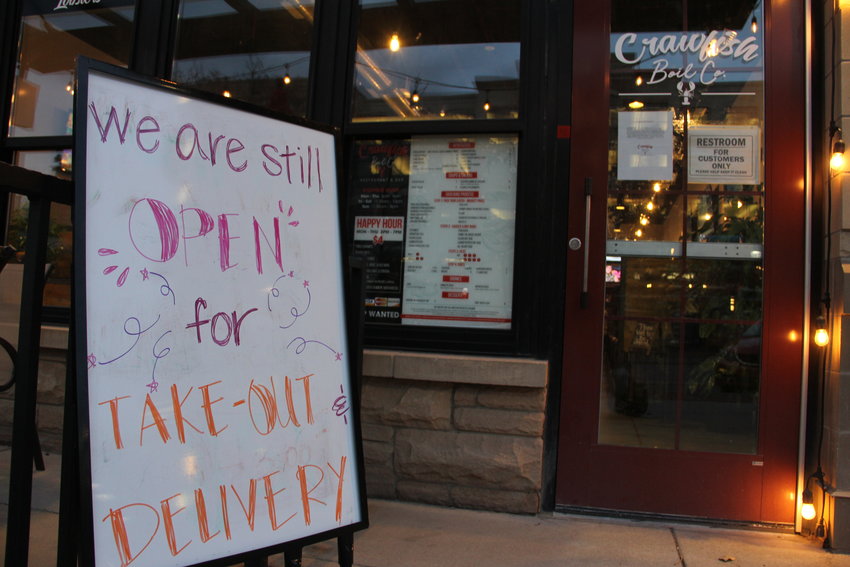 A sign outside Crawfish Boil Co. restaurant and bar reads, “We are still open for take-out and delivery.” Most businesses at The Streets at SouthGlenn are closed amid the spread of COVID-19, but many restaurants there are selling food for off-premises consumption, as they are across the state.